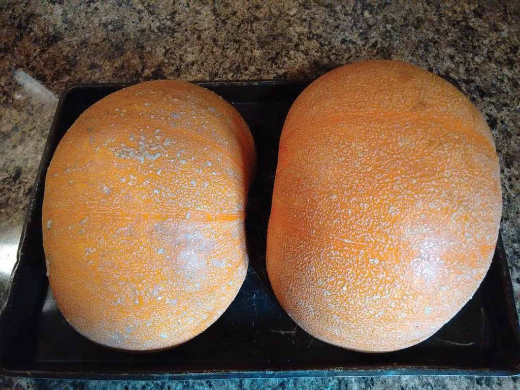 pumpkin halves ready to bake on a cookie sheet